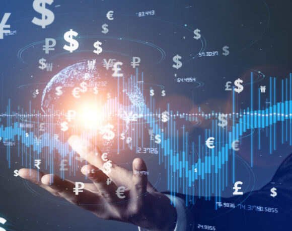 Double exposure image of a businessman holding the virtual world with symbols of money and a trade growth chart illustrating the opening of Bahrain's first Fintech Venture.