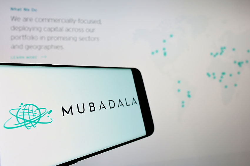 Paper presentation is being showcased on a smart screen before which a smartphone is kept with a logo Mubadala.