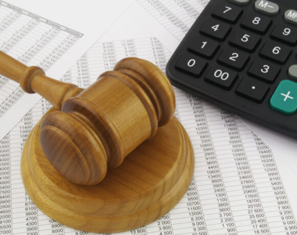 Wooden judge gavel and calculator on financial reports illustrating financial fraud concept.