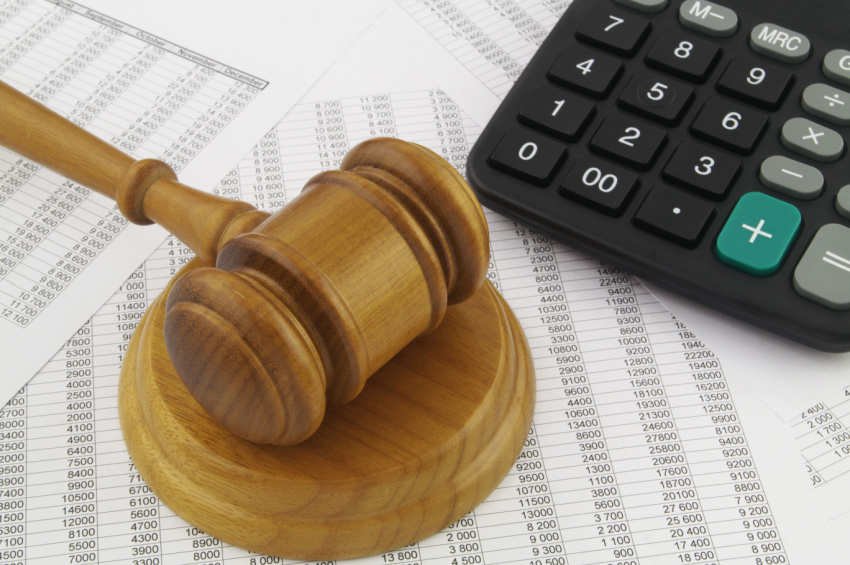 Wooden judge gavel and calculator on financial reports illustrating financial fraud concept.