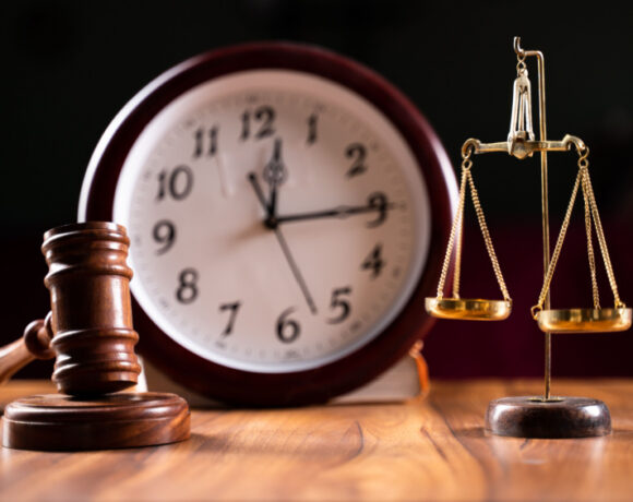 Concept showing the delay or slow in the judicial justice system by using judge hammer, balance scale and wall clock.