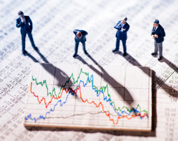 Image of tiny Businessmen miniatures looking at stock market charts illustrates the best Fintech stocks to buy at a discount.