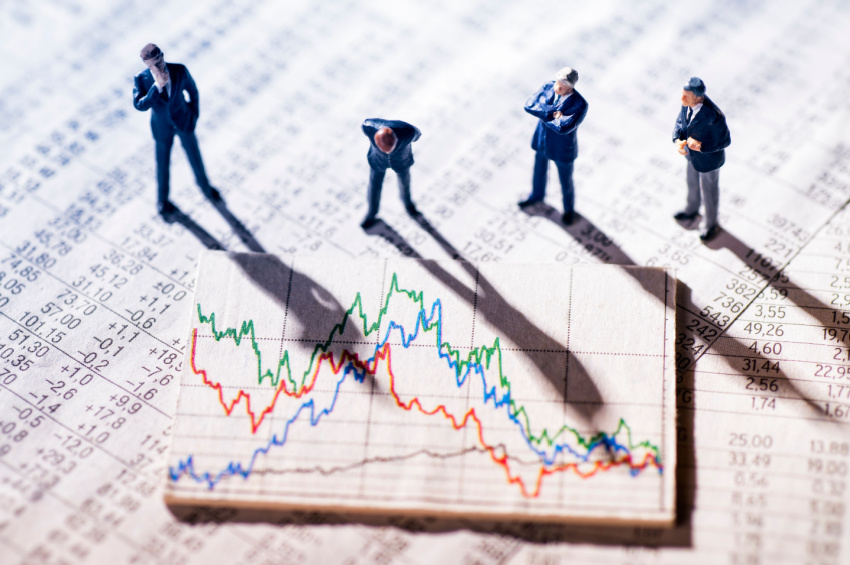Image of tiny Businessmen miniatures looking at stock market charts illustrates the best Fintech stocks to buy at a discount.
