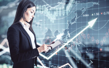 A concentrated businesswoman using a digital tablet on a virtual wall background with stock market changes illustrates the SoFi stock forecast.