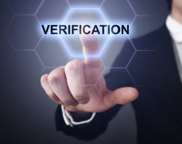 The image of a finance professional touching a digital verification button illustrates the increasing prevalence of deepfake scams.