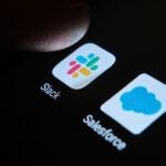 A fingertip on top of Slack and Salesforce apps on the smartphone screen illustrates Slack shareholders' lawsuit.