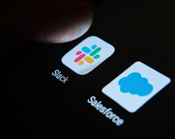 A fingertip on top of Slack and Salesforce apps on the smartphone screen illustrates Slack shareholders' lawsuit.